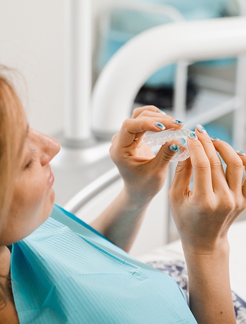 Patient holding clear aligner in treatment room